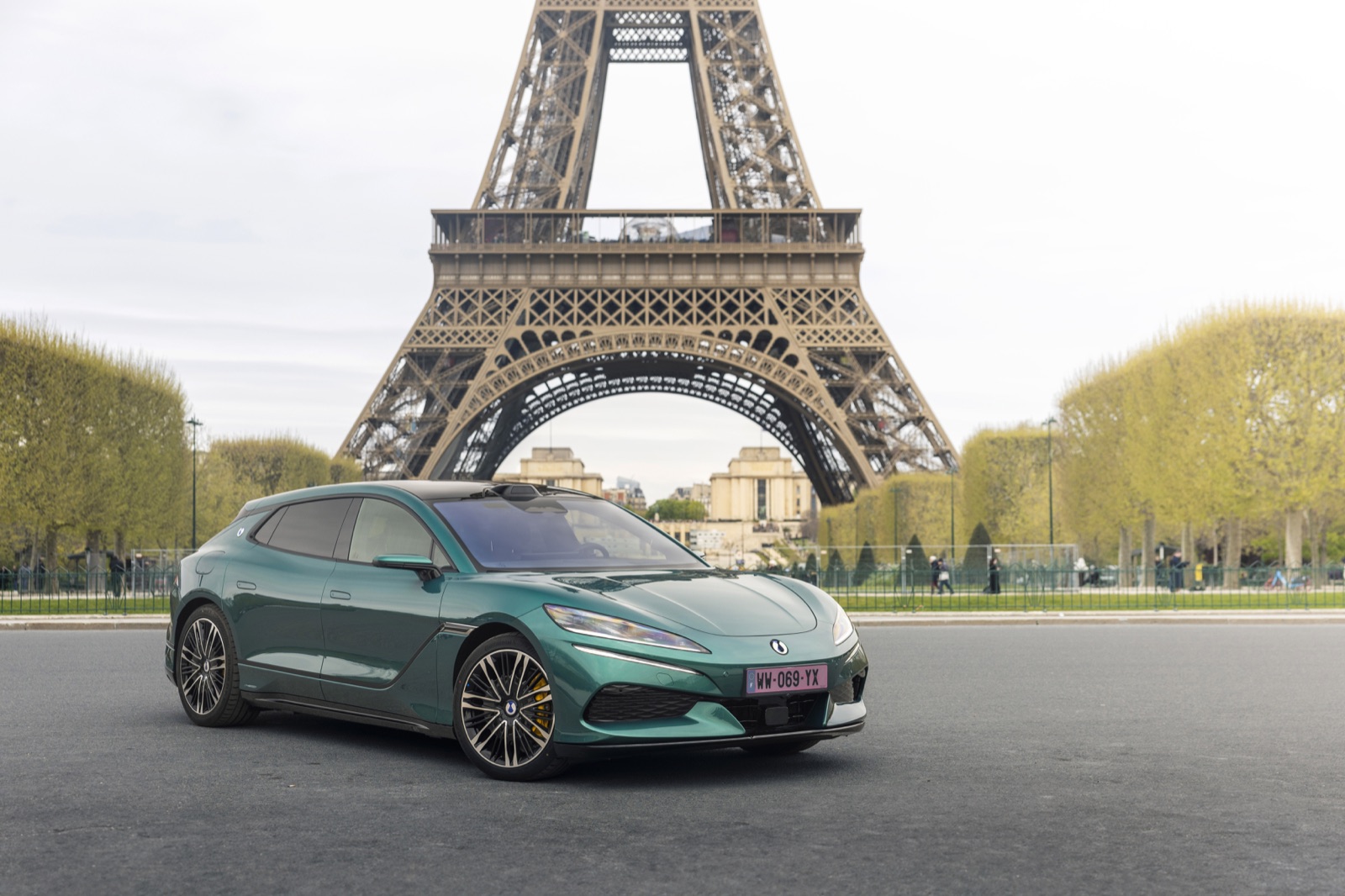 A green BYD DENZA Z9GT electric car parked in front of the Eiffel Tower in Paris