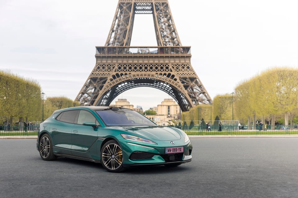 A green BYD DENZA Z9GT electric car parked in front of the Eiffel Tower in Paris